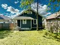 Back view of a cozy, dark-painted home with a fenced yard and manicured grass at 4814 E New York St, Indianapolis, IN 46201