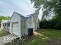 Attached one-car garage exterior with white siding, a partially tarped roof and mature trees nearby at 7607 E 46Th St, Indianapolis, IN 46226