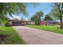 Single-story home with a long driveway, lush lawn, and mature trees offering shade at 976 Santa Maria Dr, Greenwood, IN 46143