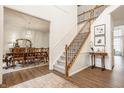 Grand foyer with elegant staircase, wood floors, and view into dining room with chandelier at 11552 Buckskin Dr, Zionsville, IN 46077