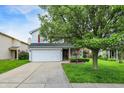 Inviting two-story home featuring a two-car garage, lush green lawn, and a mature shade tree at 15264 Ten Point Dr, Noblesville, IN 46060