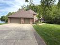 A large, brick house with a three-car garage sits at the end of a concrete driveway next to a lake at 2925 N Country Club Rd, Martinsville, IN 46151
