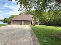 A large, brick house with a three-car garage sits at the end of a concrete driveway next to a lake at 2925 N Country Club Rd, Martinsville, IN 46151