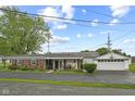 A view of the rear exterior with a long, paved driveway, a covered patio and a detached garage at 30 N Depot St, New Palestine, IN 46163