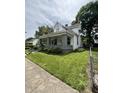 Two-story home featuring a covered porch, green lawn, and fenced yard at 303 Walnut St, Greenfield, IN 46140