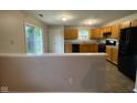 Kitchen area features oak cabinets, black appliances, vinyl flooring and sliding glass doors to outdoor patio at 356 Seabreeze Cir, Avon, IN 46123