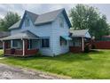 Two-story home with light blue siding, brick porch columns, well maintained yard, and mature trees at 5 E Jefferson St, Maxwell, IN 46154