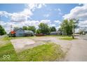 Two-story home with light blue siding, next to a parking area, set amongst green trees under a blue sky at 5 E Jefferson St, Maxwell, IN 46154