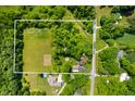 Expansive aerial view of a wooded property featuring a home, pool, large lawn area and agricultural space with a white border at 5253 W 8Th Street Rd, Anderson, IN 46011