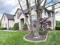 Elegant white brick home with manicured landscaping, mature trees, and a well-maintained lawn at 7823 Ashtree Dr, Indianapolis, IN 46259