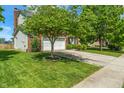 Well-maintained home with lush green lawn and mature trees lining the driveway to a two-car garage at 8376 Glen Highlands Dr, Indianapolis, IN 46236