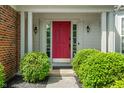 Elegant front entrance boasts a vibrant red door, classic sidelights, and manicured green bushes at 8376 Glen Highlands Dr, Indianapolis, IN 46236