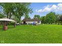 Large, grassy backyard with mature trees offering shade and a gazebo, ideal for relaxation at 9130 E 18Th St, Indianapolis, IN 46229