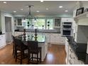 Bright kitchen featuring white cabinets, black countertops, stainless steel appliances, and hardwood floors at 9510 Copley Dr, Indianapolis, IN 46260