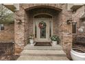 Inviting entryway with decorative wreath, potted plants, and stylish outdoor lighting at 1344 S Fox Paw Dr, New Palestine, IN 46163