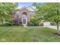 Traditional brick home boasting a covered entrance, arched window, and professionally landscaped front yard at 14353 Chariots Whisper Dr, Carmel, IN 46074