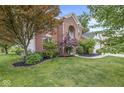 Well-maintained brick home showcasing mature trees and manicured landscaping at 14353 Chariots Whisper Dr, Carmel, IN 46074