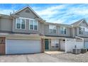 Inviting townhome features a one-car garage, green door, and charming white picket fence, creating a welcoming curb appeal at 2306 Brightwell Pl, Indianapolis, IN 46260