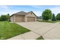 Spacious driveway leading to a three-car garage, surrounded by a lush green lawn at 2422 Oak Dr, Clayton, IN 46118