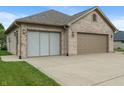 Close-up of the brick three-car garage with tan garage doors and concrete driveway at 2422 Oak Dr, Clayton, IN 46118