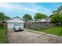 View of detached two car garage and brick house with a fenced yard and paved driveway at 3602 N Colorado Ave, Indianapolis, IN 46218
