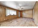 Bright living room with hardwood floors, paneled walls, and a large window letting in plenty of light at 5558 Bertha St, Indianapolis, IN 46241