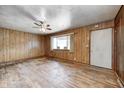Spacious living room features hardwood floors, paneled walls, a ceiling fan, and a large window for ample natural light at 5558 Bertha St, Indianapolis, IN 46241