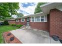 Inviting brick home entrance featuring a concrete steps and manicured landscaping at 5903 Schoolwood Dr, Speedway, IN 46224