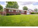 Traditional brick ranch home featuring a lush green lawn and landscaped shrubbery at 5903 Schoolwood Dr, Speedway, IN 46224