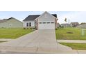 Home exterior with a long concrete driveway, leading to a two car garage, complimented by a green lawn at 637 N Quartz Ln, Fortville, IN 46040