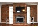Close up shot of a brick fireplace with built-in shelving and a mounted television at 7443 Country Brook Dr, Indianapolis, IN 46260