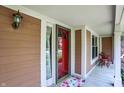 Inviting covered front porch featuring a vibrant red door, decorative lighting, and outdoor seating at 8331 Tequista Ct, Indianapolis, IN 46236