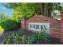 Neighborhood signage in brick with planted flowers reads ROXBURY at 9774 Foxboro Ln, Fishers, IN 46038