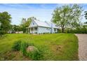 Quaint blue home showcasing a lush green lawn and a long driveway leading up to the house at 11720 S County Road 396 E, Muncie, IN 47302