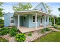 Charming light blue home featuring a porch with flower baskets and beautifully landscaped stone garden at 11720 S County Road 396 E, Muncie, IN 47302