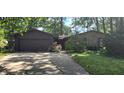 Charming home featuring a stone facade and a two-car garage surrounded by mature trees and lush landscaping at 1619 Crest Ct, Indianapolis, IN 46214
