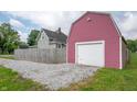 View of the detached garage with a barn-style roof, alongside a gravel driveway at 3360 Main St, Plainfield, IN 46168