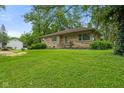 A stone-clad house sits on a lush green lawn surrounded by mature trees and landscaping at 3841 S Sherman Dr, Indianapolis, IN 46237