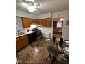 Well-lit kitchen with wooden cabinets, black appliances, a glass dining table, and a glimpse of the living room at 4113 W 30Th St, Indianapolis, IN 46222