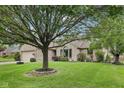 Well maintained single story home with a large shade tree, green lawn and manicured shrubs at 412 Sonhatsett Dr, Westfield, IN 46074