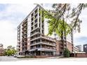 A contemporary condo building featuring multiple balconies and street-level retail space, with a tree adding natural beauty at 435 Virginia Ave # 106, Indianapolis, IN 46203