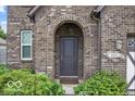 Close-up of the front door framed by an archway, surrounded by lush greenery and manicured shrubs at 4689 Muscatine Way, Westfield, IN 46062