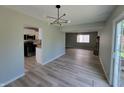 Open-concept living room with hardwood floors, modern light fixture, and a view of the kitchen at 5239 Traditions Rd, Indianapolis, IN 46235