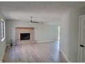 Bright living room featuring hardwood floors, fireplace with brick surround, and a ceiling fan at 5239 Traditions Rd, Indianapolis, IN 46235