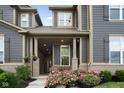 Inviting front porch with brick columns, flowering bushes, and seating area at front door at 7152 Cherry Creek Blvd, Carmel, IN 46033