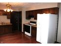 Cozy kitchen with dark wood cabinets, white appliances, and hardwood flooring at 7931 Guion Rd, Indianapolis, IN 46268