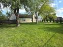 Large grassy backyard with trees. The house has beige vinyl siding, a chimney, and a patio at 892 Millbrook Dr, Avon, IN 46123