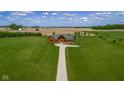 Drone shot shows log cabin on a vast lawn with ample space and surrounding farm fields at 8981 N 325 E, Columbus, IN 47203