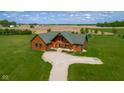An aerial view reveals the log home set in a large manicured lawn with an expansive farm field beyond at 8981 N 325 E, Columbus, IN 47203