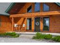 Inviting front porch featuring chairs, with the log home's entrance visible at 8981 N 325 E, Columbus, IN 47203